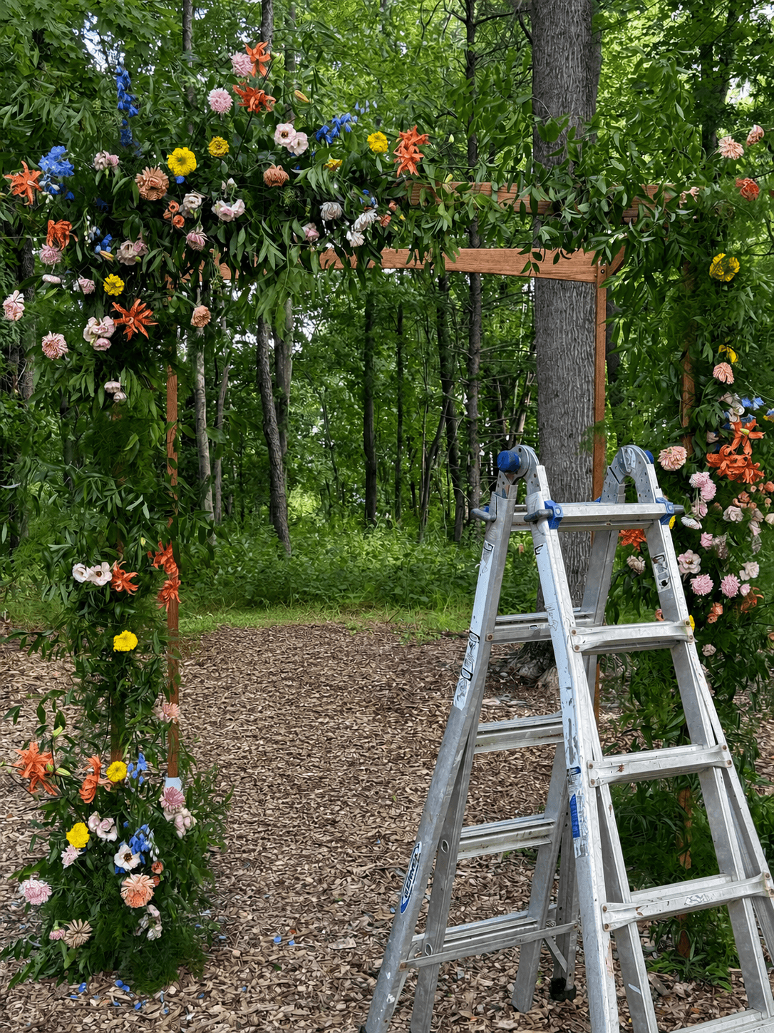 Floral wedding arch and ladders during breakdown at a wooded Hudson Valley venue